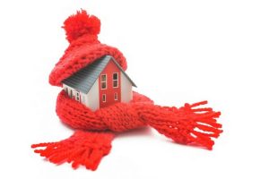 Miniature house wrapped in a red knitted scarf and hat, symbolizing winter home insulation and heating tips for homeowners in Holmdel, NC.