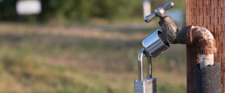 Outdoor faucet with a padlock, emphasizing outdoor plumbing maintenance for spring.