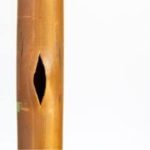 Close-up of a light brown bamboo flute with finger hole, highlighting natural craftsmanship.