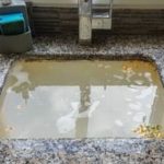 Kitchen sink with stagnant murky water and debris, highlighting plumbing issues for Force Plumbing and Heating LLC.