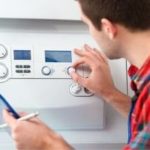Technician adjusting digital control panel while performing water heater maintenance for Force Plumbing and Heating LLC.