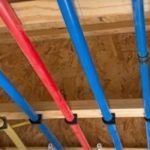 Colorful red, blue, and yellow pipes mounted on wood, illustrating plumbing details for Force Plumbing and Heating LLC.