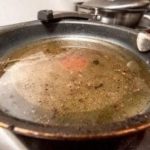 Used frying pan with oil and food remnants, highlighting common cooking messes related to plumbing issues.