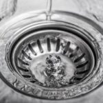 Shiny circular sink drain with swirling water, showcasing plumbing tips from Force Plumbing and Heating LLC.