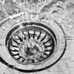 Close-up of a circular drain with flowing water, highlighting plumbing maintenance for home plumbing issues.