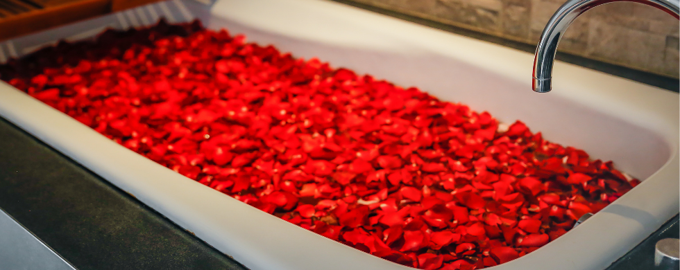 Modern bathtub filled with bright red rose petals in a clean bathroom, highlighting luxury and relaxation for homeowners.