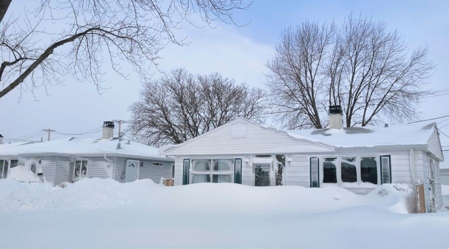 Two traditional houses in a snow-covered landscape, showcasing residential plumbing and heating maintenance potential.