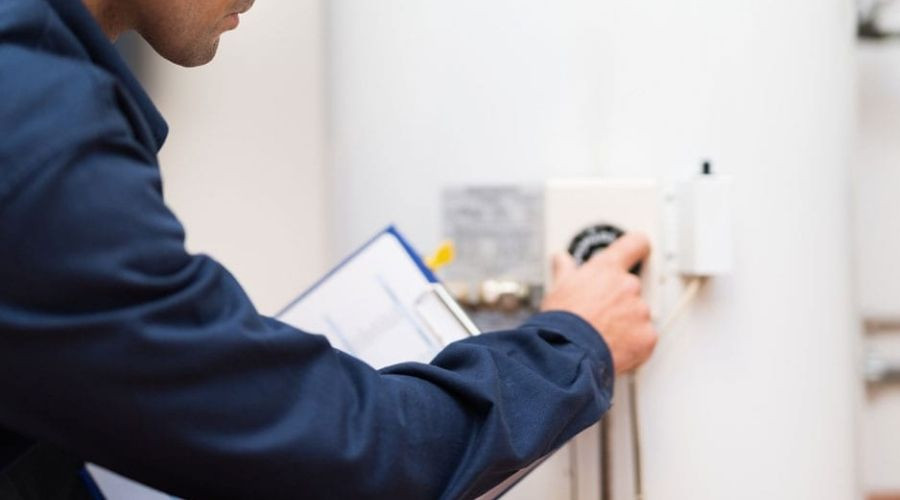 Technician in coveralls inspecting a control panel for plumbing maintenance at Force Plumbing and Heating LLC.