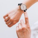 Human hands point at a minimalist watch, showcasing elegance for bathroom remodeling professionals.