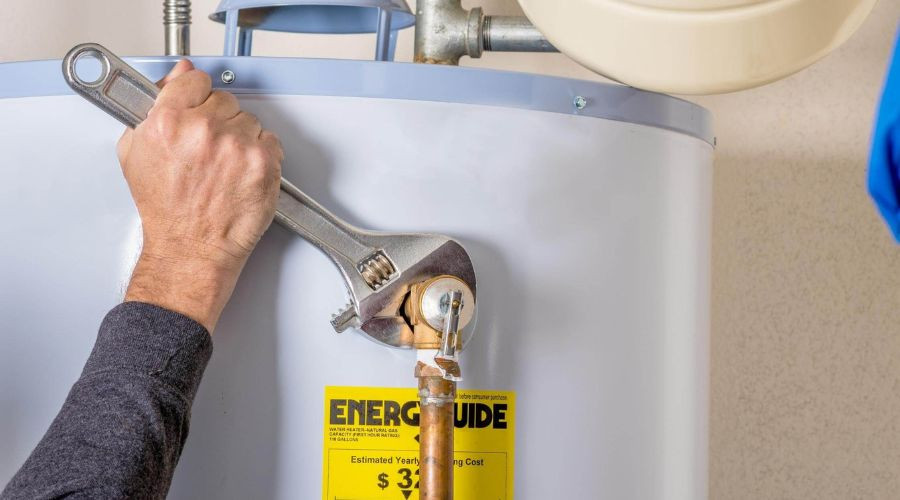 Person using adjustable wrench on energy-efficient water heater with Energy Guide label at Force Plumbing and Heating LLC.