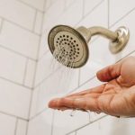 Hand under showerhead with running water, illustrating plumbing issues by Force Plumbing and Heating LLC.