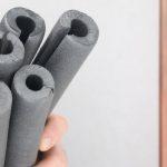 Hand holding five dark gray foam tubes, useful for winter-proofing plumbing systems at Force Plumbing and Heating LLC.