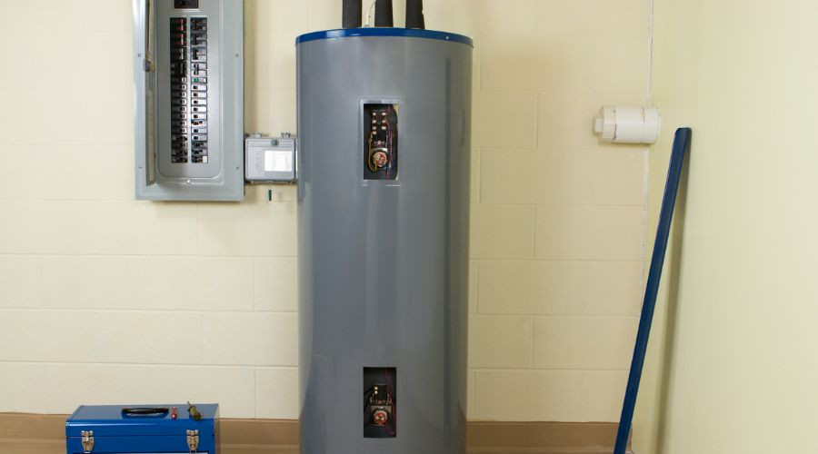 Gray hot water heater and electrical panel in a utility room, with toolbox nearby, by Force Plumbing and Heating.