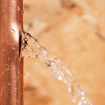 Copper pipe with a visible water leak, illustrating the need for prompt plumbing repairs to prevent damage and water waste.