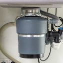 Garbage disposal unit installed under kitchen sink, showcasing plumbing connections and maintenance accessibility, relevant to plumbing services and maintenance tips.