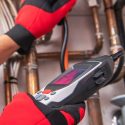 Technician using a diagnostic tool on plumbing pipes, showcasing expertise in plumbing and heating services, relevant to Force Plumbing and Heating LLC's offerings.