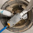 Sump pump installation and maintenance in a sump pit, showcasing plumbing components and water level, relevant to spring rain preparations.